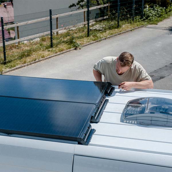 Julius, Ehemann von Muriel, von twoanavan prüft die beiden ECTIVE 190 SSP Solarmodule mit Schindel Technologie auf dem Dach des Mercedes-Benz Sprinter.